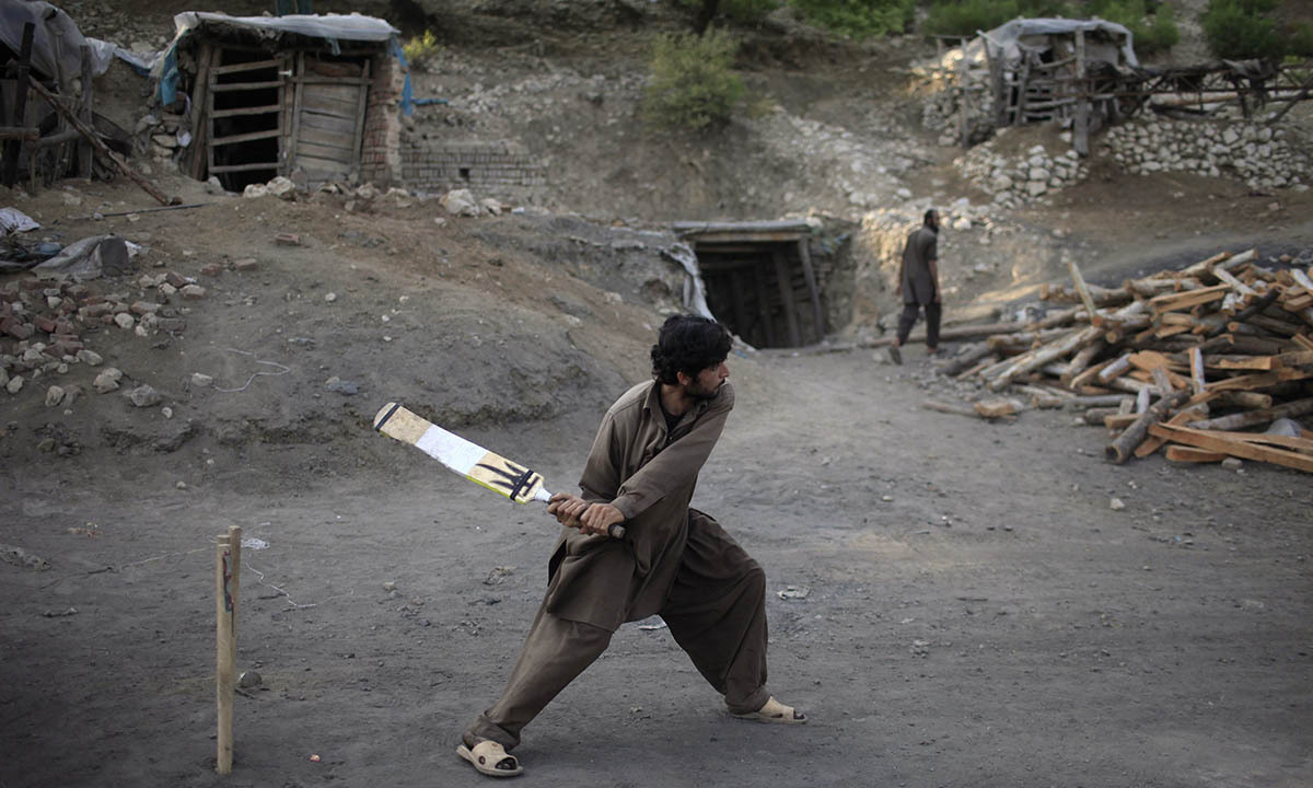 A miner plays cricket in the evening at a coal field in Choa Saidan Shah, Punjab province
