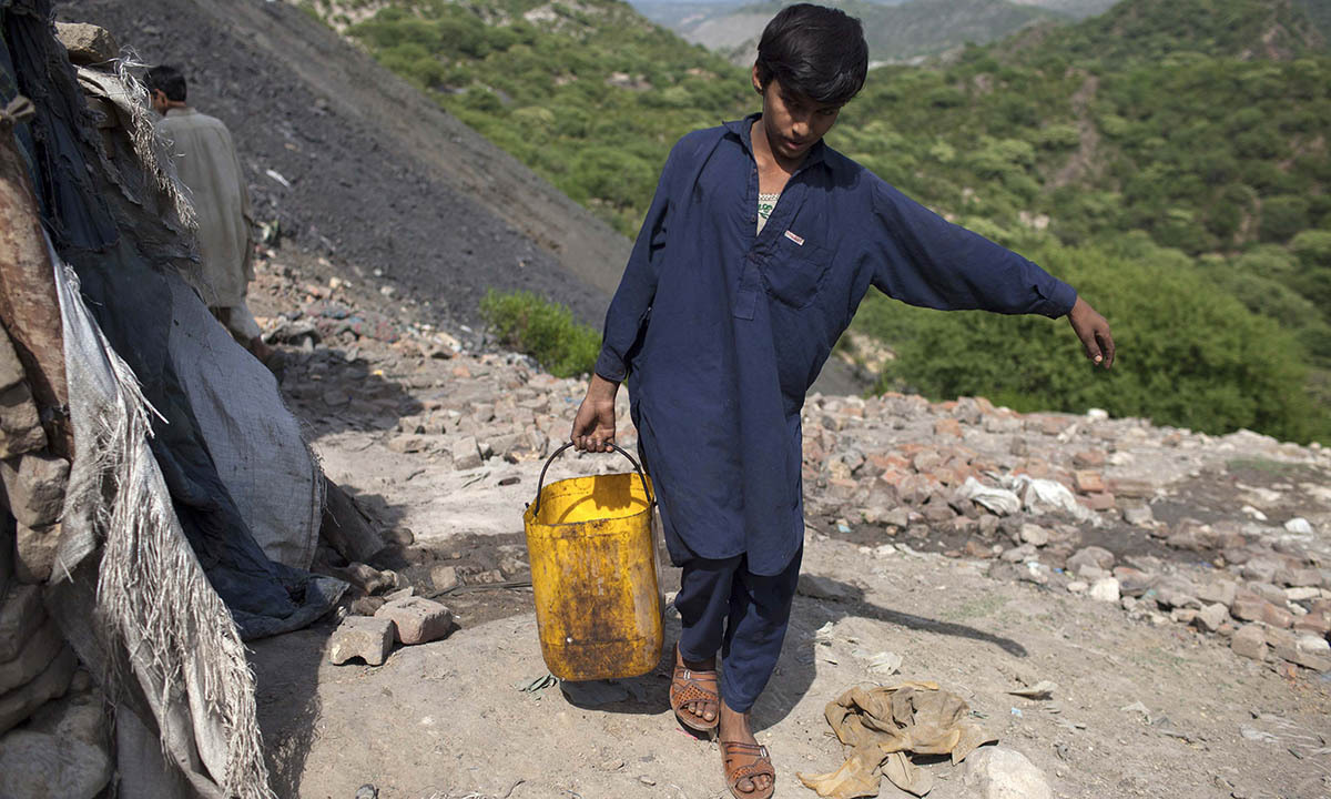 Samiullah carries water for his uncle's bath at a coal field in Choa Saidan Shah, Punjab province