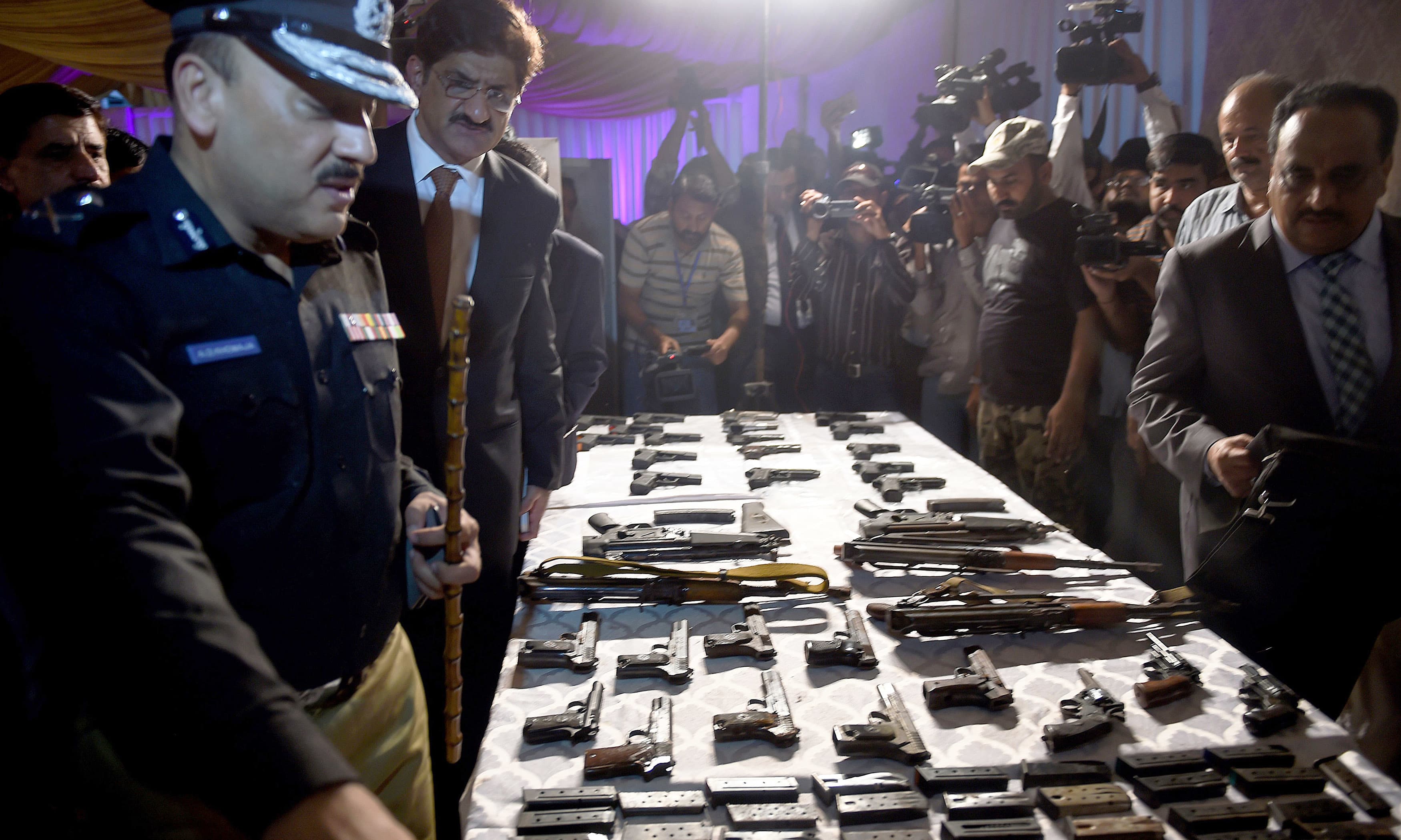 Chief minister of the southern Sindh province Pakistan, Syed Murad Ali Shah (2L) and police officials look at recovered weapons from arrested militants, belonging to a group linked to Islamic State (IS) jihadists in Karachi on November 7, 2016. Pakistan police have arrested two militants accused of assassinating one of the country's best known Sufi musicians, a top provincial official said. Amjad Sabri, a renowned Qawwal or sufi singer was shot in June 2016 by two gunmen riding a motorcycle as he drove his car to a TV studio where he was due to perform for a Ramadan show. / AFP PHOTO / RIZWAN TABASSUM
